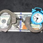 Handcuffs,,money,and,alarm,clock,on,dark,background,,bail,concept