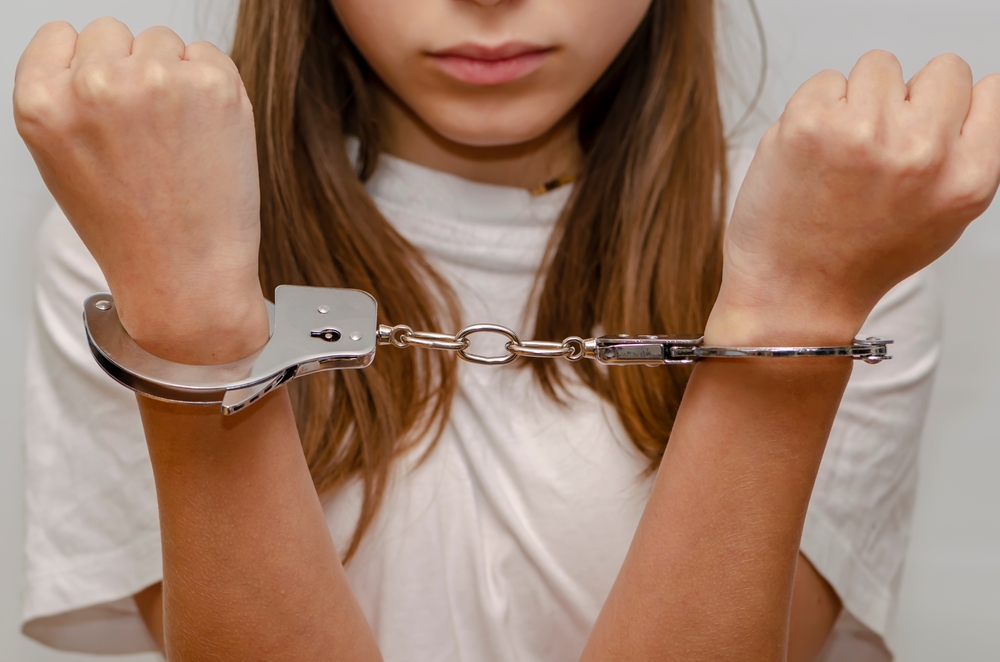 Teenage,girl,in,handcuffs,on,gray,background.,juvenile,delinquent,,criminal